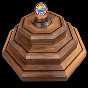 Actual finished BraveCraft three-tier walnut display on black, holder installed. Chamfered edges and recessed coin grooves. Coins not included.